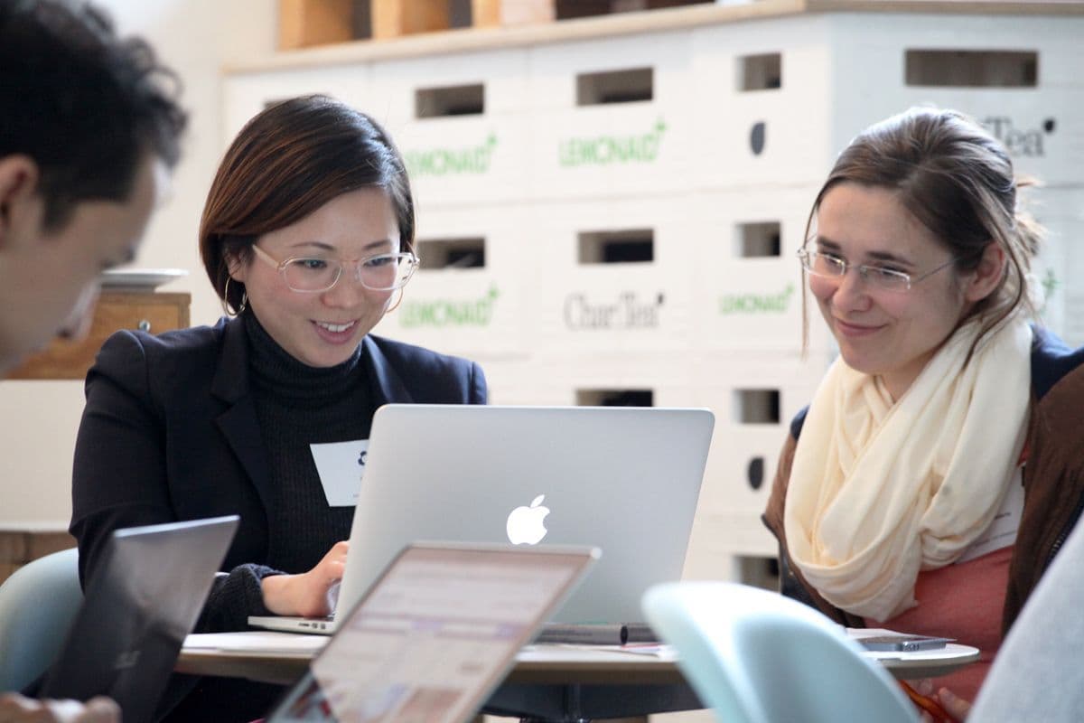 Picture with two female read people in front of a screen.