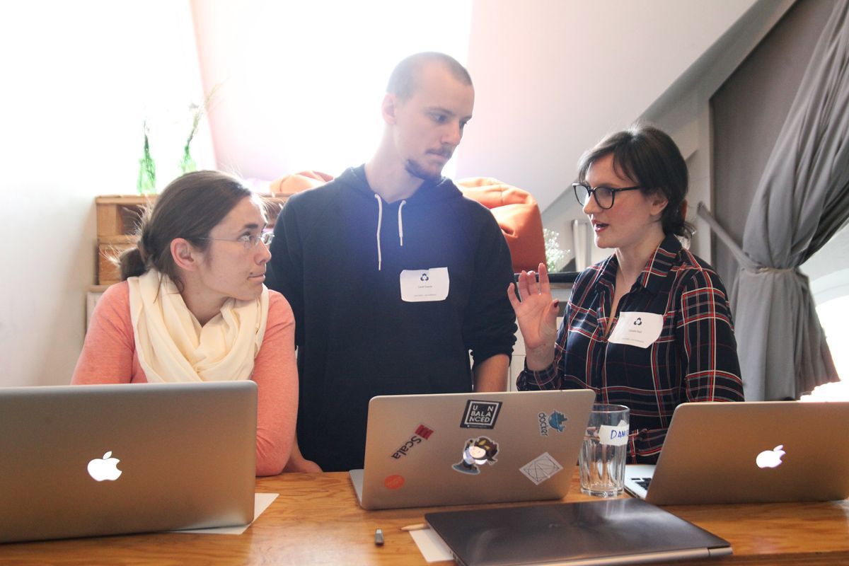 three people standing in front of their laptops engaged in conversation